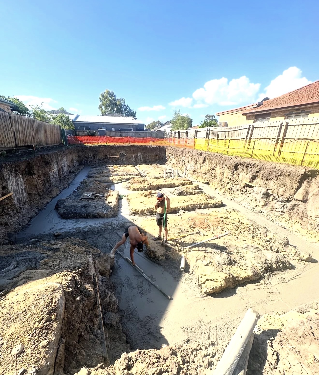 Workers pouring concrete footings on residential site