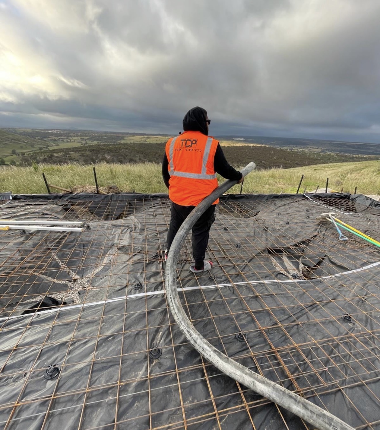 TCP worker with concrete pump hose on reinforced slab